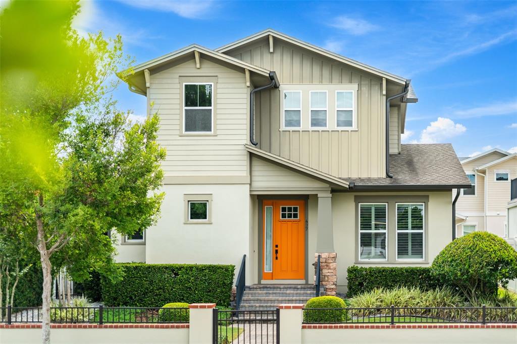 A two-story house with light-colored siding, a bright orange front door, and a metal fence — 437 N CAPEN AVENUE, WINTER PARK, FL
