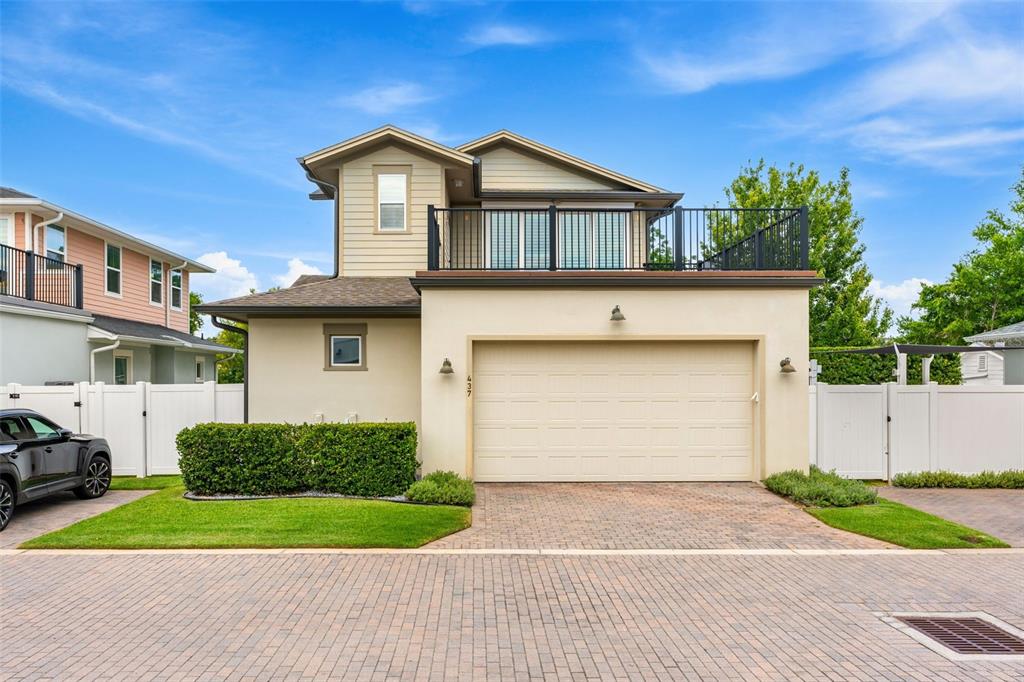 A two-story house with a beige stucco facade, a two-car garage, and an upper balcony — 437 N CAPEN AVENUE, WINTER PARK, FL