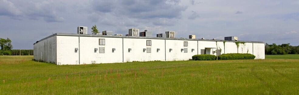 A long, single-story white concrete block industrial building sits in a grassy field — 3809 SE County Road 255, FL 32340, FL