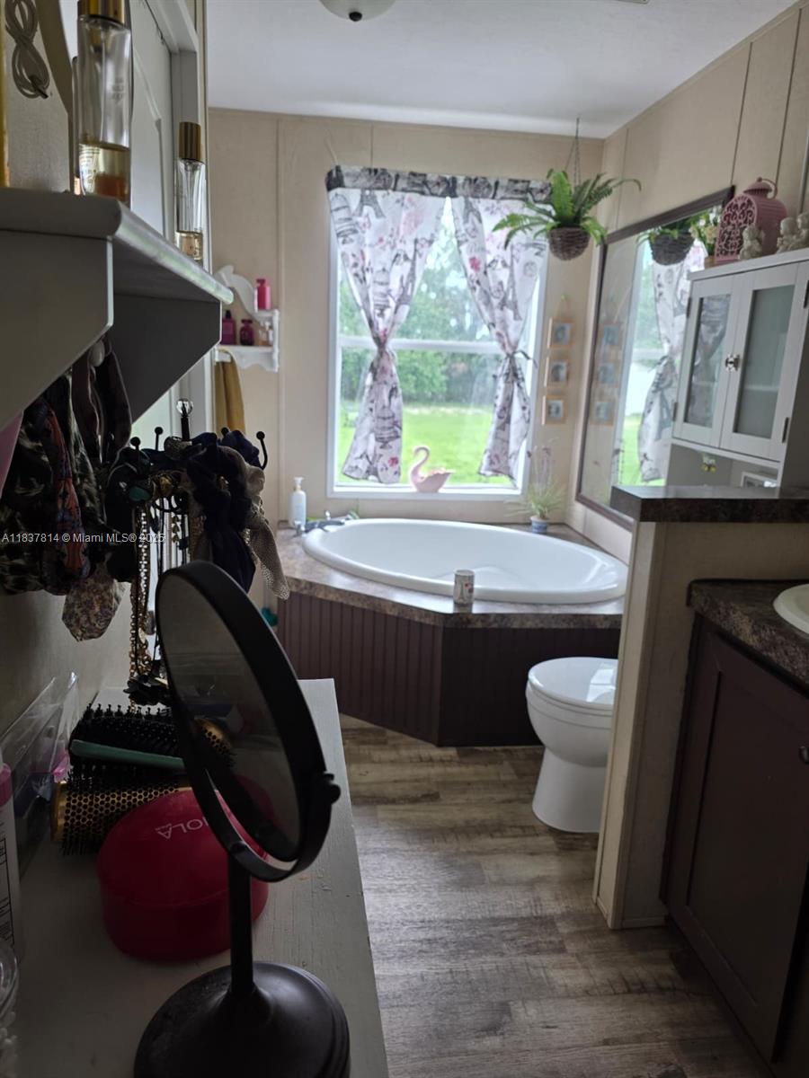 A bathroom features a corner soaking tub, a toilet, and a vanity with a mirror — 648 Avenida del Sur, Clewiston FL 33440, CLEWISTON, FL