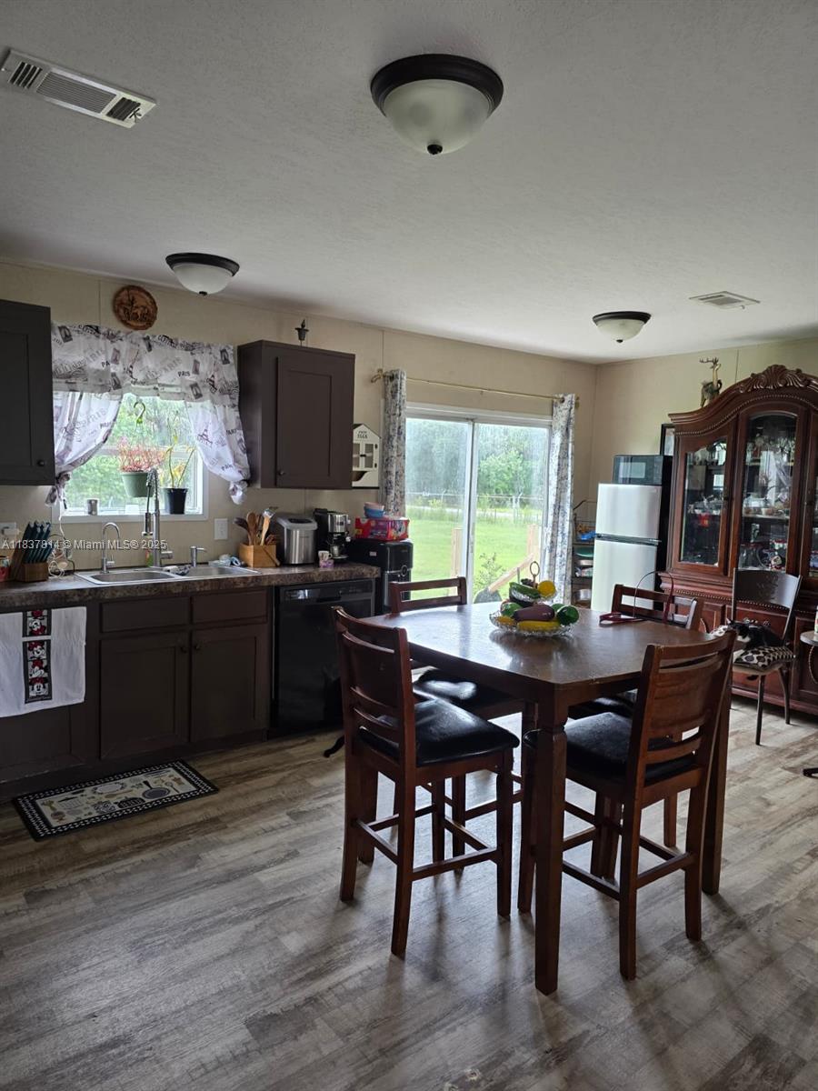 A kitchen with dark cabinets, a dining table, and a sliding glass door to the outside — 648 Avenida del Sur, Clewiston FL 33440, CLEWISTON, FL