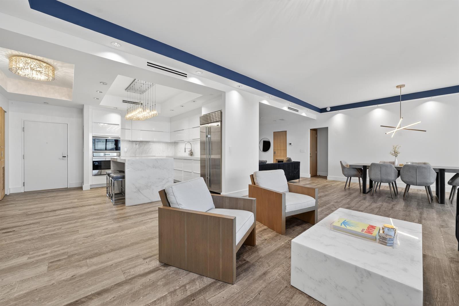 An open-concept living area features a white marble kitchen island, dining set, and wood flooring — 2301 Collins Avenue, Miami Beach FL 33139, MIAMI BEACH, FL
