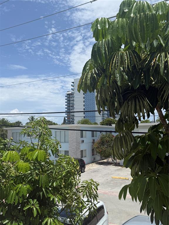 An exterior view shows a parking lot, a light blue apartment building, and tall trees — 7350 GARY AVENUE, MIAMI BEACH, FL