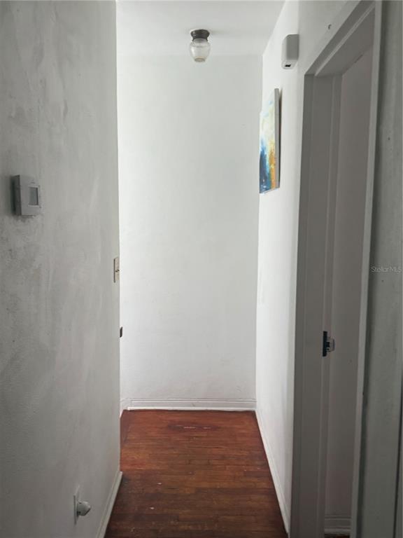 A narrow hallway with white walls, hardwood flooring, and a single ceiling light fixture — 7350 GARY AVENUE, MIAMI BEACH, FL