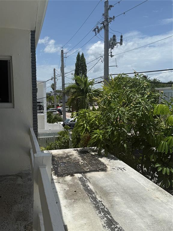 A view from a balcony overlooking a flat roof, utility poles, and lush green trees — 7350 GARY AVENUE, MIAMI BEACH, FL