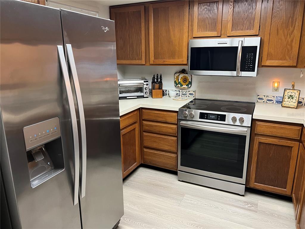 A kitchen features stainless steel appliances, wood cabinets, and light-colored flooring — 333 WOODLAKE WYNDE, OLDSMAR, FL