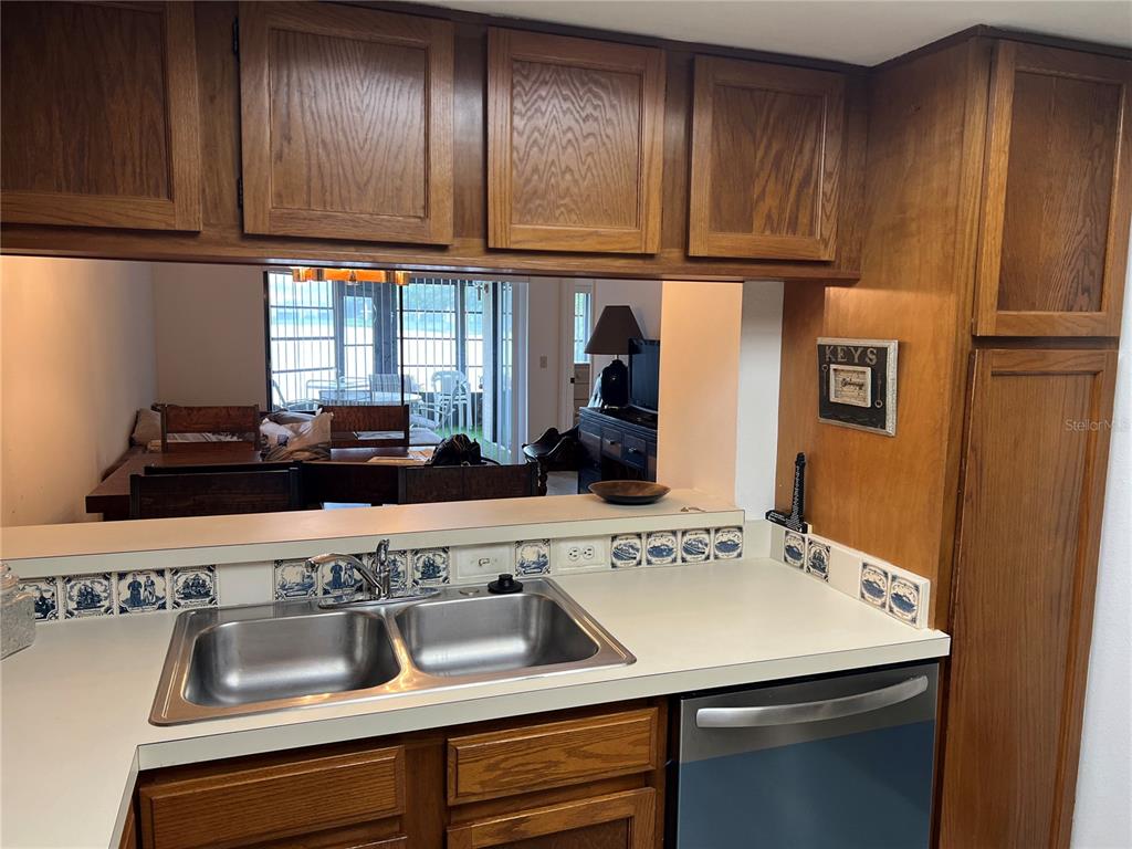 A kitchen features wood cabinets, a double-basin sink, and decorative blue and white tiles — 333 WOODLAKE WYNDE, OLDSMAR, FL
