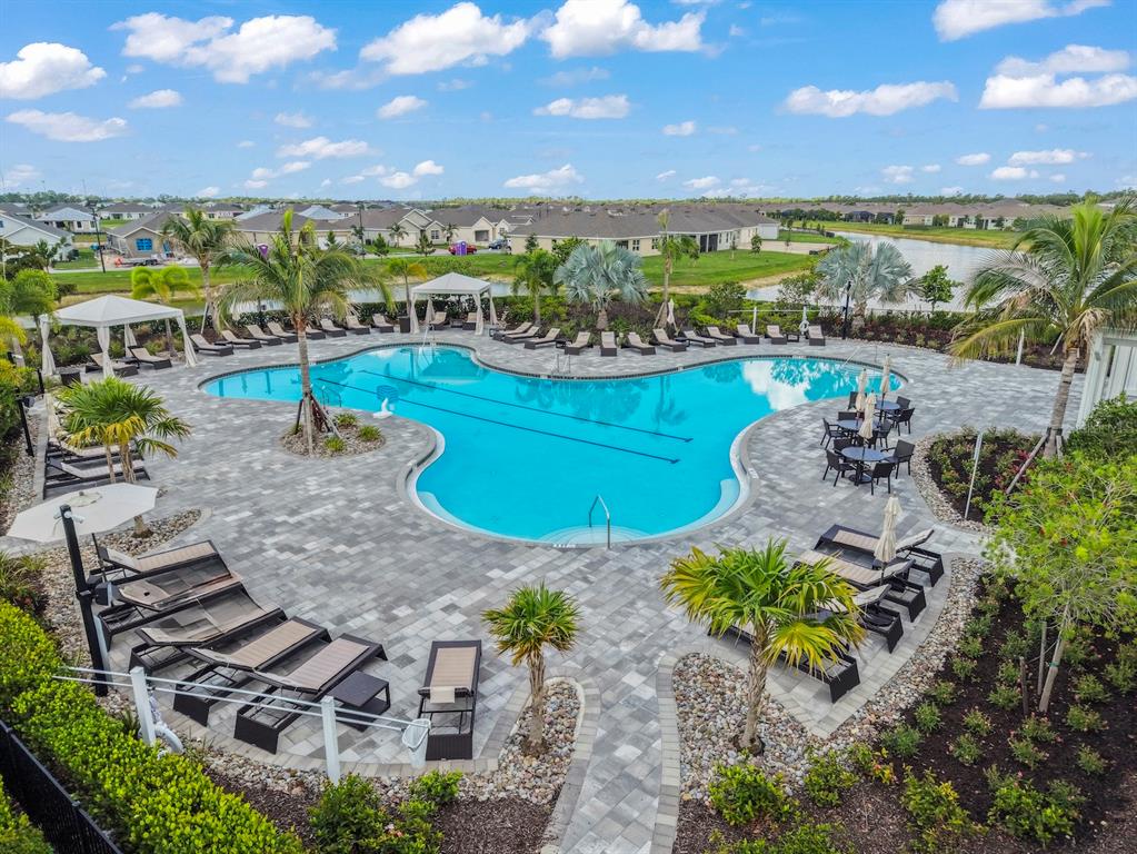 An outdoor swimming pool with lounge chairs and palm trees on a paved patio — 1422 POWELL VALLEY DRIVE, PORT CHARLOTTE, FL