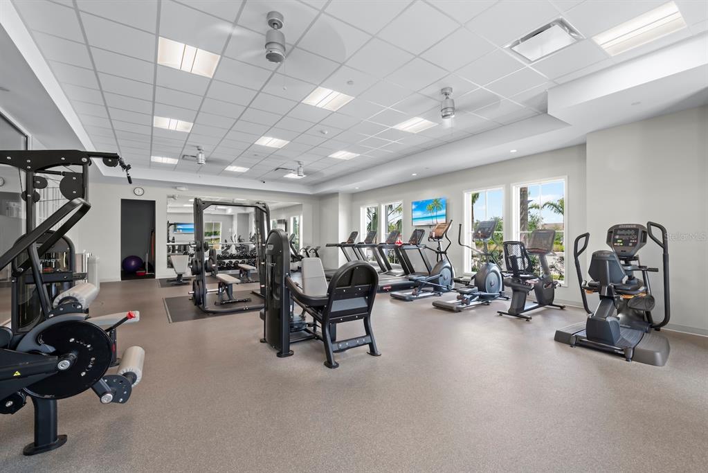 A fitness center features various exercise machines, a drop ceiling with recessed lighting, and windows — 1422 POWELL VALLEY DRIVE, PORT CHARLOTTE, FL