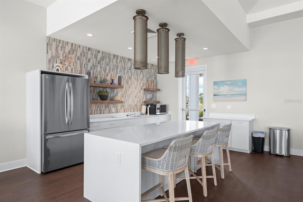 A modern kitchen features a white island with bar seating, stainless appliances, and tiled backsplash — 1422 POWELL VALLEY DRIVE, PORT CHARLOTTE, FL