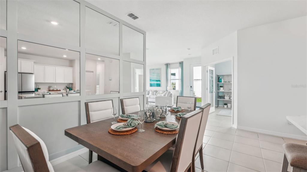 A dining room features a wooden table, upholstered chairs, and a mirrored wall partition — 33042 RUSTIC RISE ROAD, SAN ANTONIO, FL