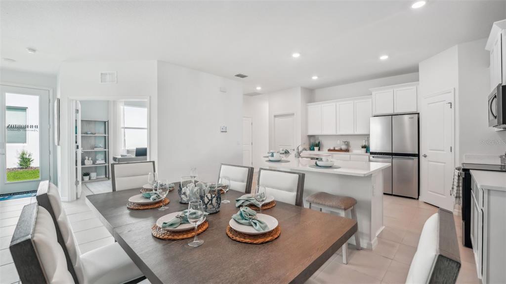 A dining area with a wooden table sits in front of an open-concept kitchen — 33042 RUSTIC RISE ROAD, SAN ANTONIO, FL