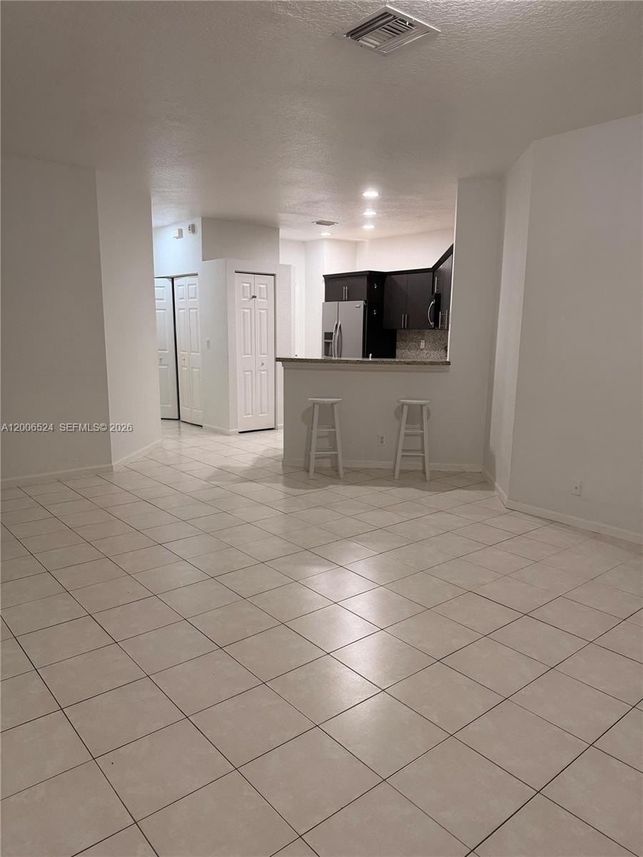 An open-concept living area features light-colored floor tiles and a kitchen with dark cabinetry — 9040 NW 54th St, Sunrise FL 33351, SUNRISE, FL