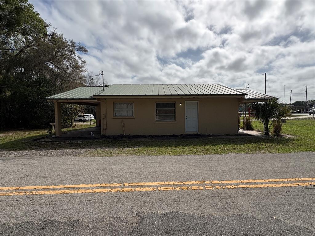 A single-story tan house with a green metal roof and a side carport — 131 N C 470, LAKE PANASOFFKEE, FL