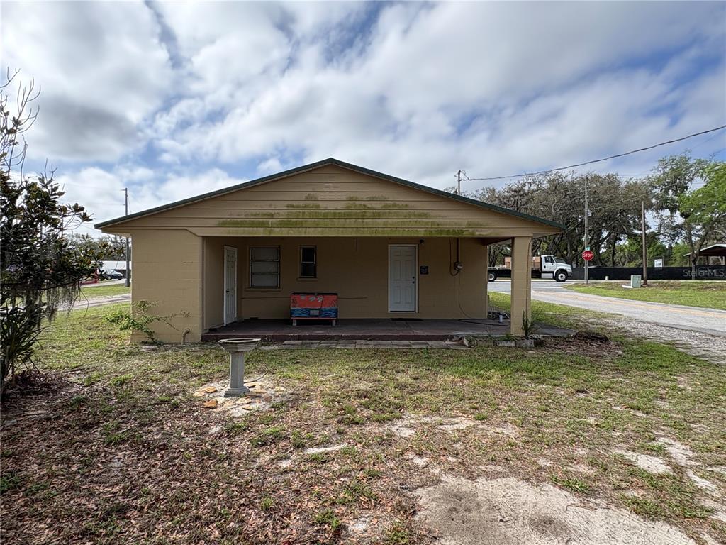 A tan, single-story house features a covered front porch, a birdbath, and a grassy yard — 131 N C 470, LAKE PANASOFFKEE, FL