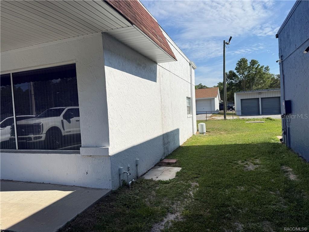 The exterior of a white building features a side yard leading to a detached garage — 3161 E GULF TO LAKE HIGHWAY, INVERNESS, FL