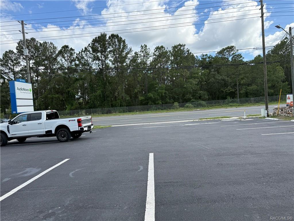 A paved parking lot sits in front of a road with a wooded background — 3161 E GULF TO LAKE HIGHWAY, INVERNESS, FL
