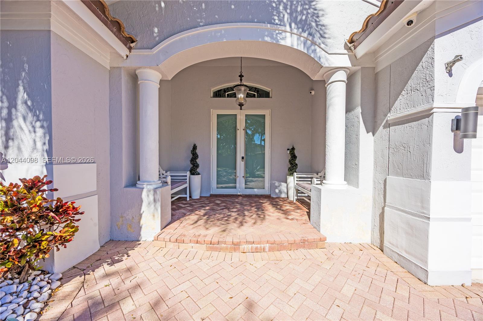 A covered entryway features a brick-paved porch, two white columns, and double glass doors — 12235 SW 121st Ter, Miami FL 33186, MIAMI, FL