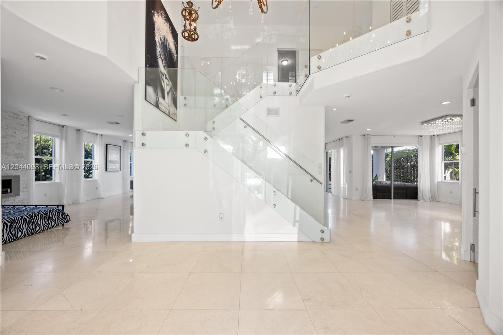 A bright, open-concept living area features a glass-railed staircase and polished tile flooring — 12235 SW 121st Ter, Miami FL 33186, MIAMI, FL