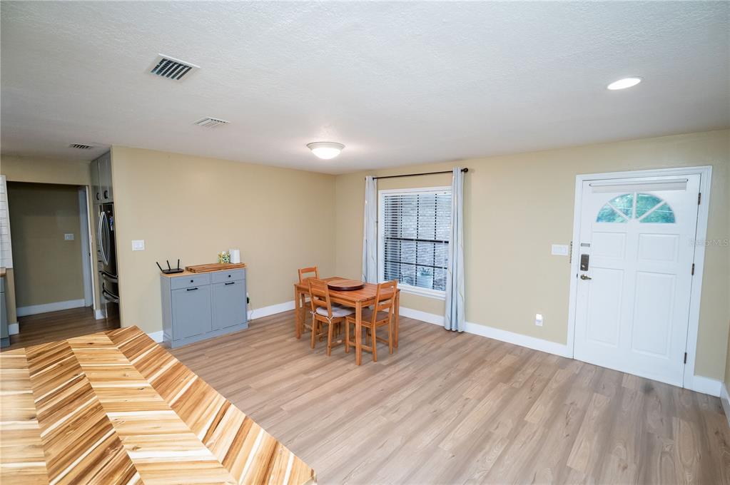 A dining area features light wood-look flooring, a small wooden table, and a white door — 23816 OAK TREE DRIVE, SORRENTO, FL