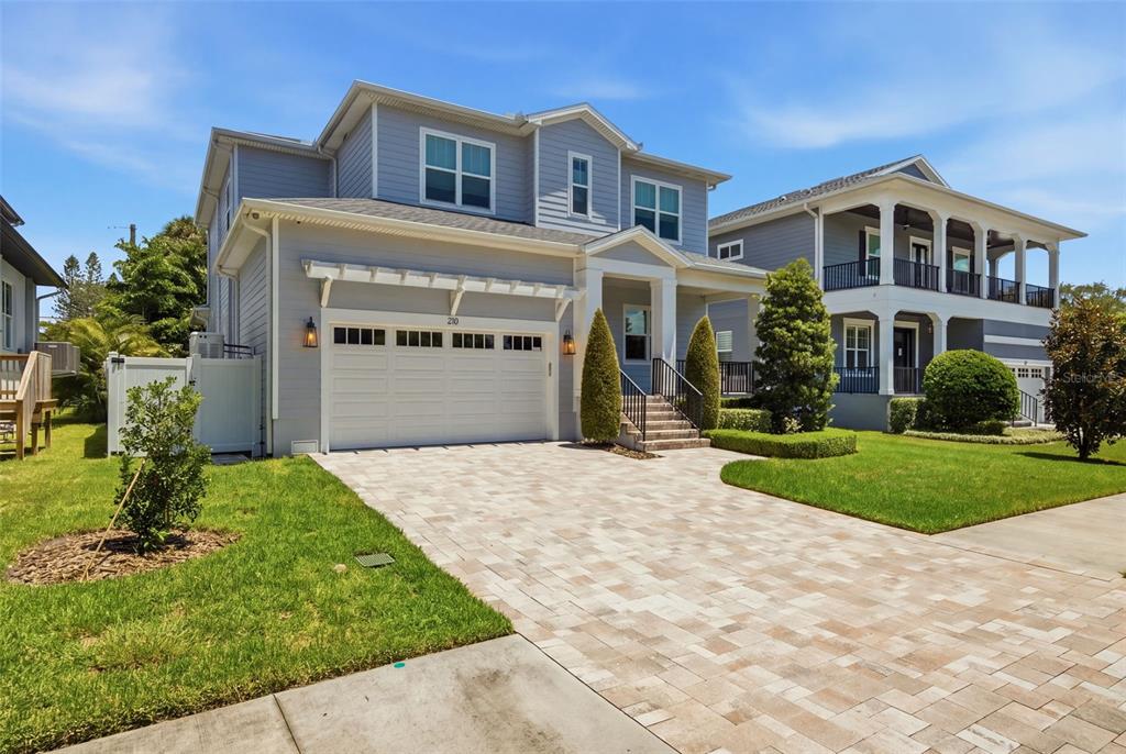 A two-story light blue house with a paved driveway and a white garage door — 210 S SHORE CREST DRIVE, TAMPA, FL
