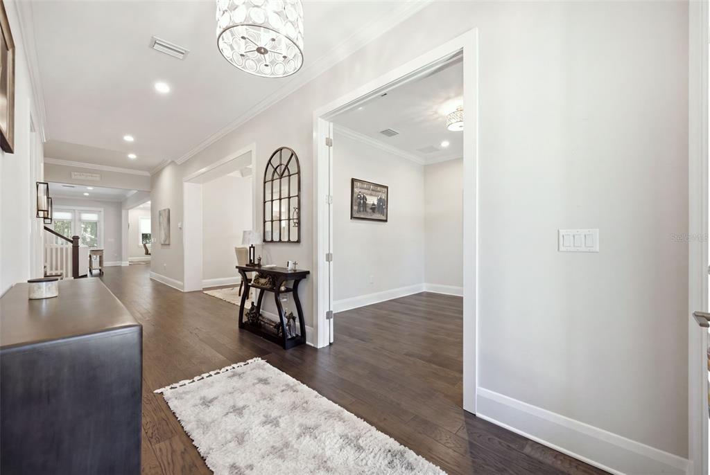 A bright hallway with dark hardwood floors leads to an open room with a decorative mirror — 210 S SHORE CREST DRIVE, TAMPA, FL