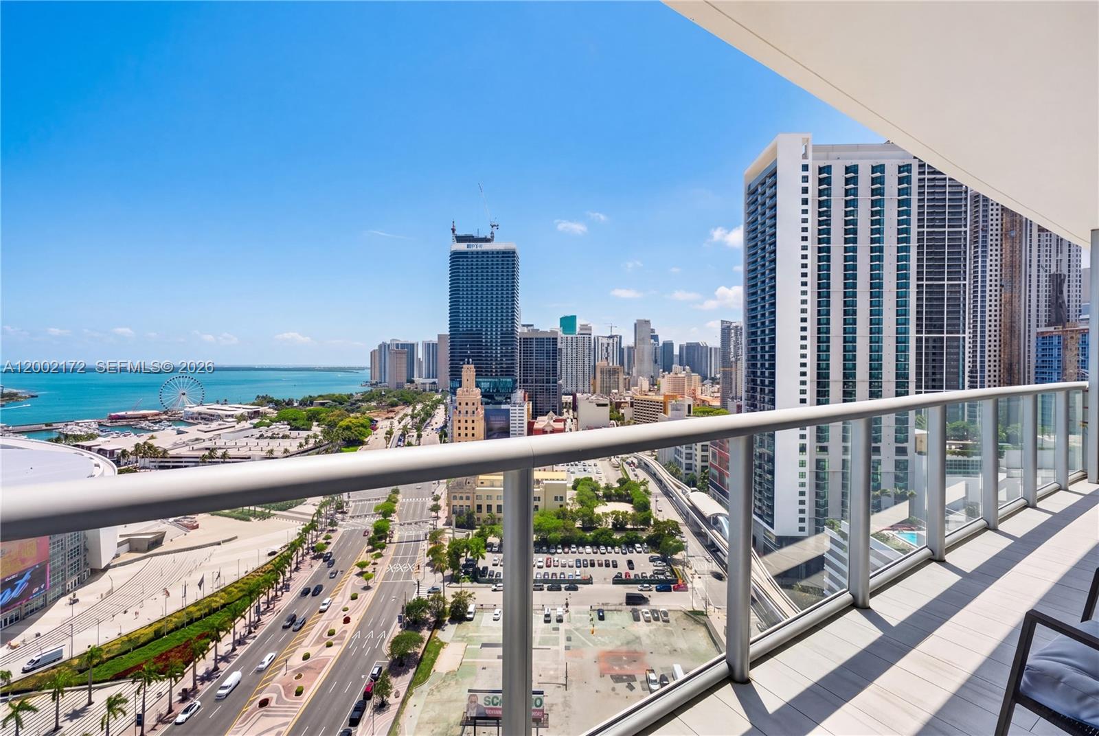 A high-rise balcony overlooks a city street, a parking lot, and the ocean — 888 Biscayne Blvd # 2404, Miami FL 33132, MIAMI, FL