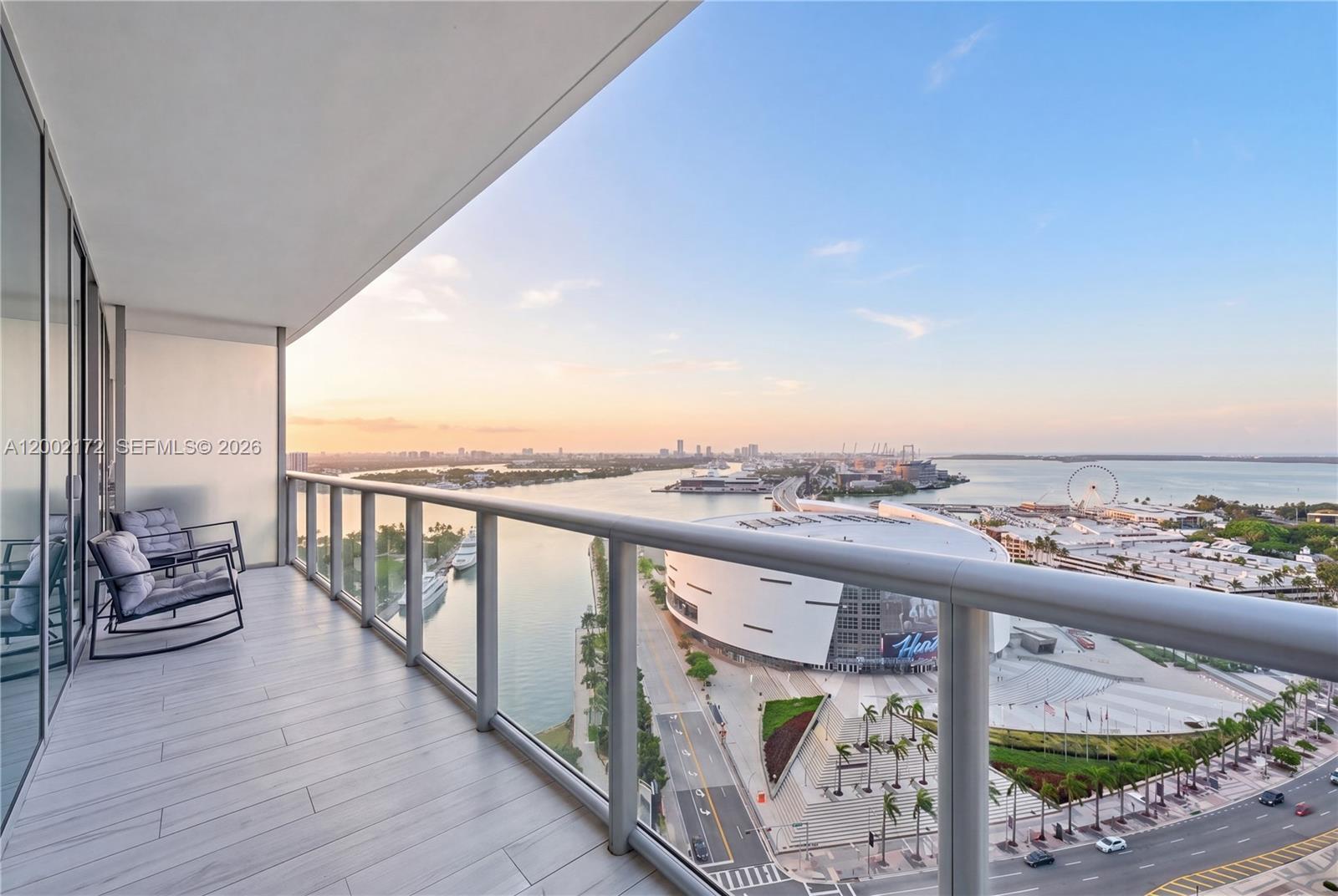 A balcony with two rocking chairs overlooks the Kaseya Center and Biscayne Bay in Miami — 888 Biscayne Blvd # 2404, Miami FL 33132, MIAMI, FL