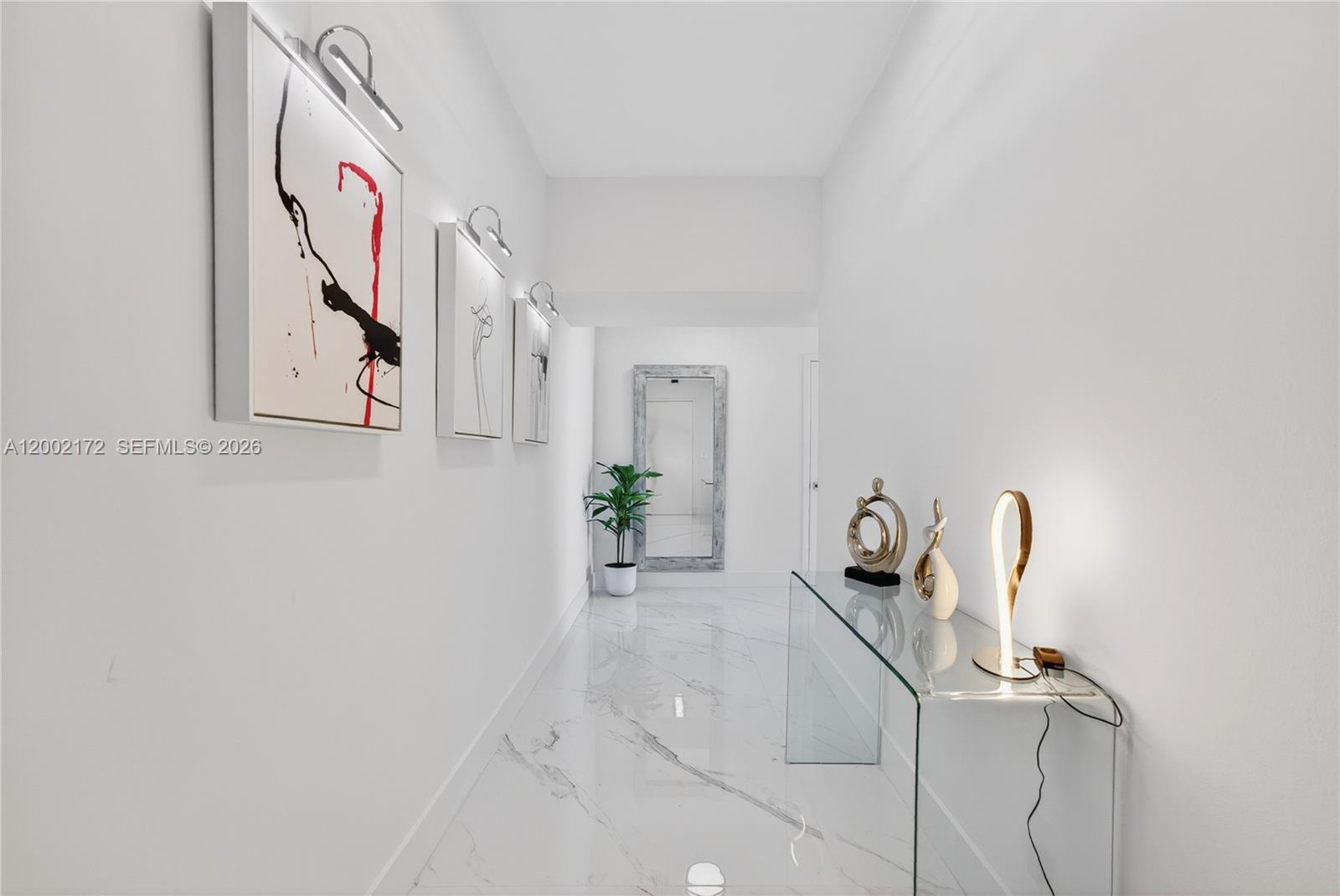 A bright, white hallway features marble-look tile flooring, a glass console table, and wall art — 888 Biscayne Blvd # 2404, Miami FL 33132, MIAMI, FL