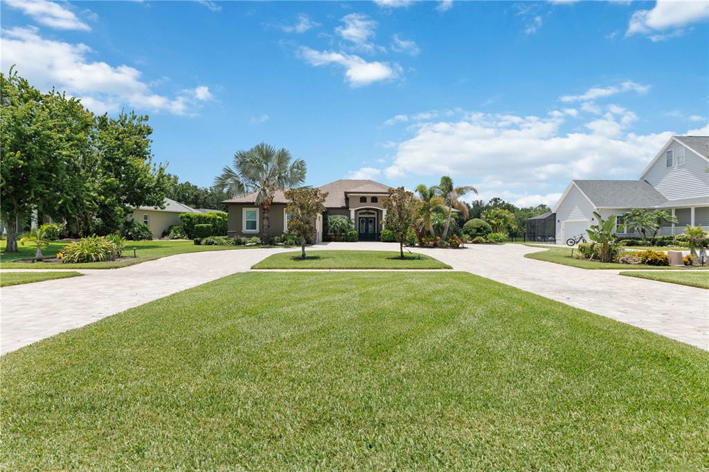 A single-story house with a paved circular driveway and a large front lawn — 15415 MULHOLLAND ROAD, PARRISH, FL