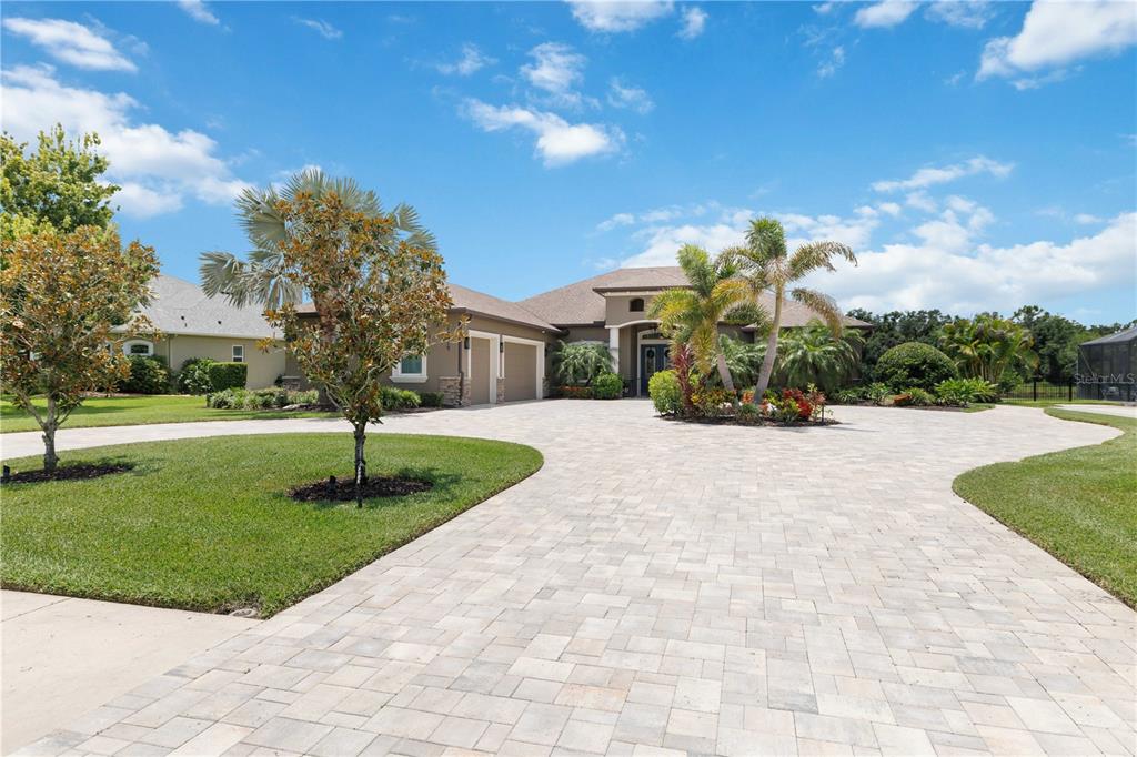 A single-story house with a paved driveway, palm trees, and a multi-car garage — 15415 MULHOLLAND ROAD, PARRISH, FL