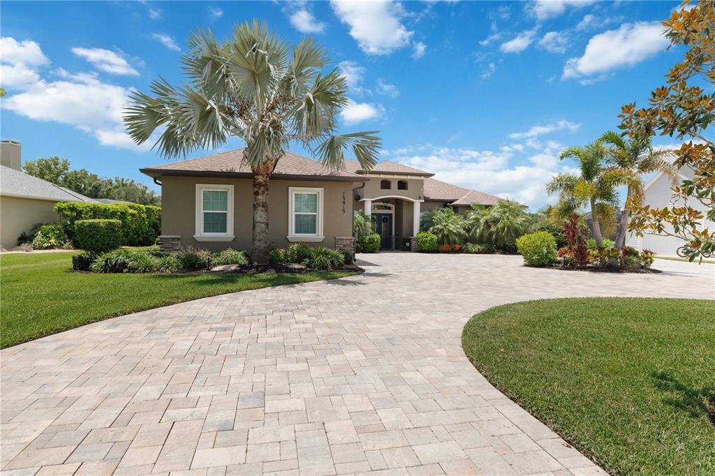 A single-story house with a paved driveway, palm trees, and a landscaped front yard — 15415 MULHOLLAND ROAD, PARRISH, FL