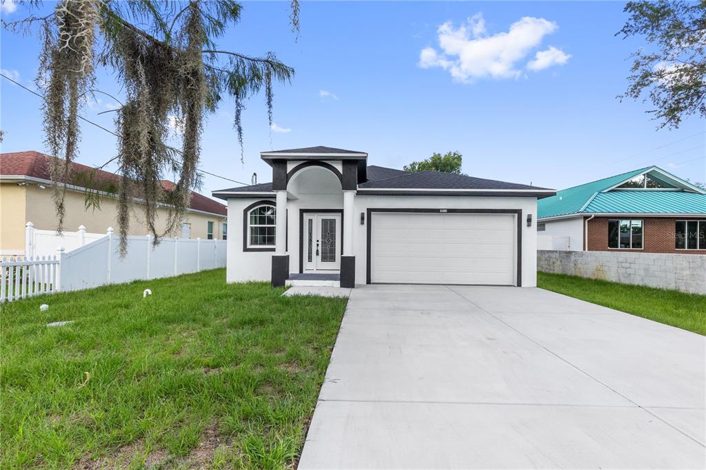 A single-story house with a white stucco exterior, dark trim, and a concrete driveway — 8314 N PADDOCK AVENUE, TAMPA, FL