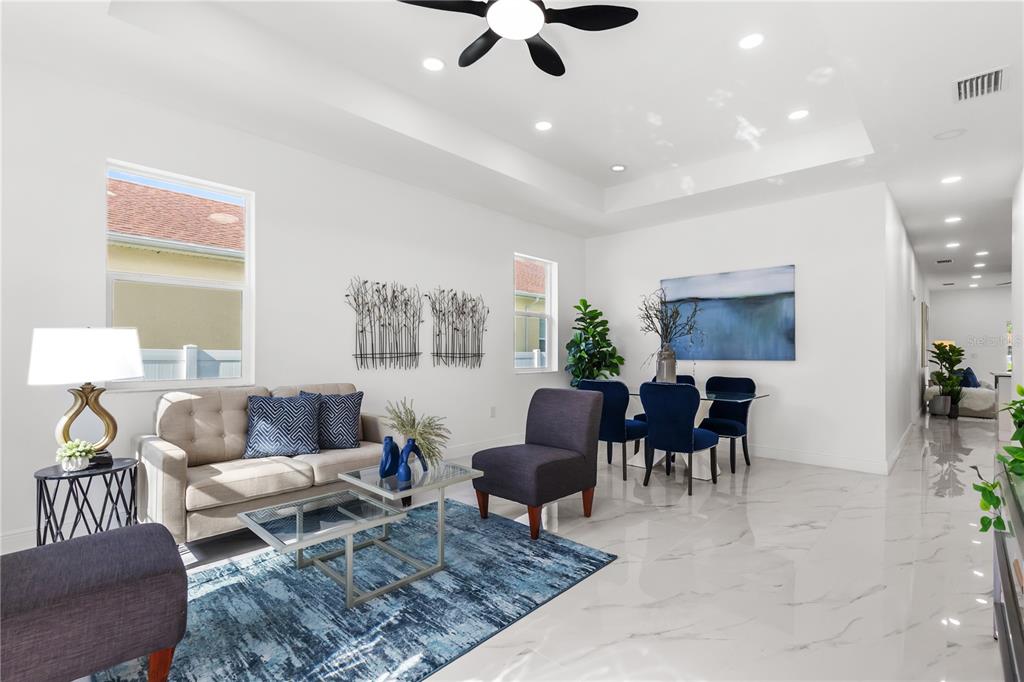 A bright living and dining area features white walls, marble floors, and blue accents — 8314 N PADDOCK AVENUE, TAMPA, FL