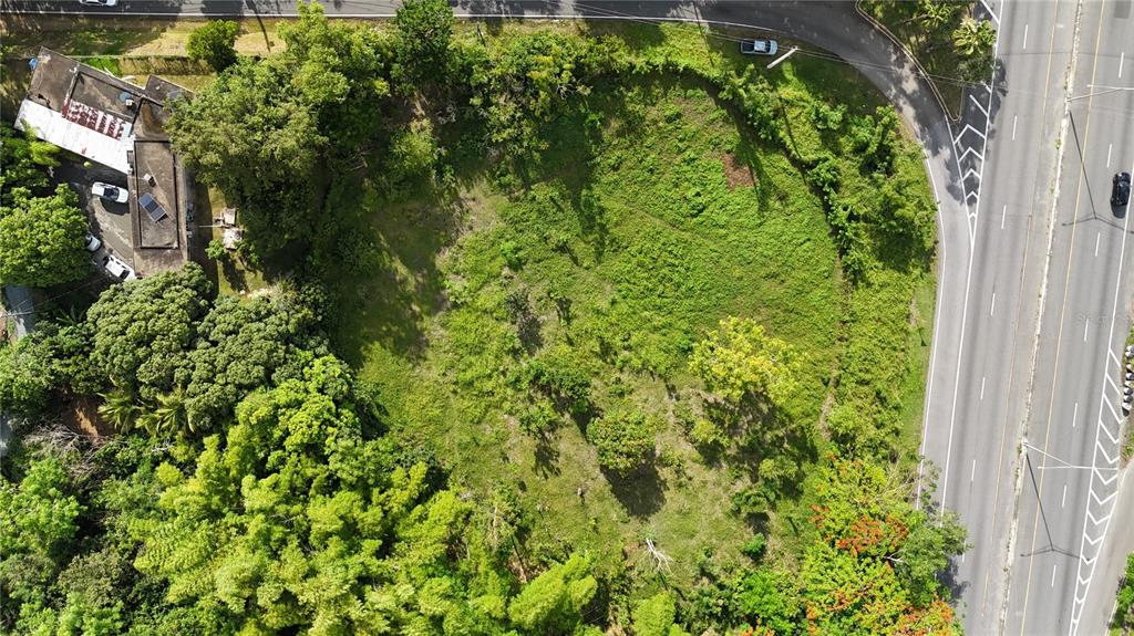 An aerial view shows a vacant, grassy lot bordered by trees and a multi-lane highway — PR 2 KM 175.4, SAN GERMAN, PR
