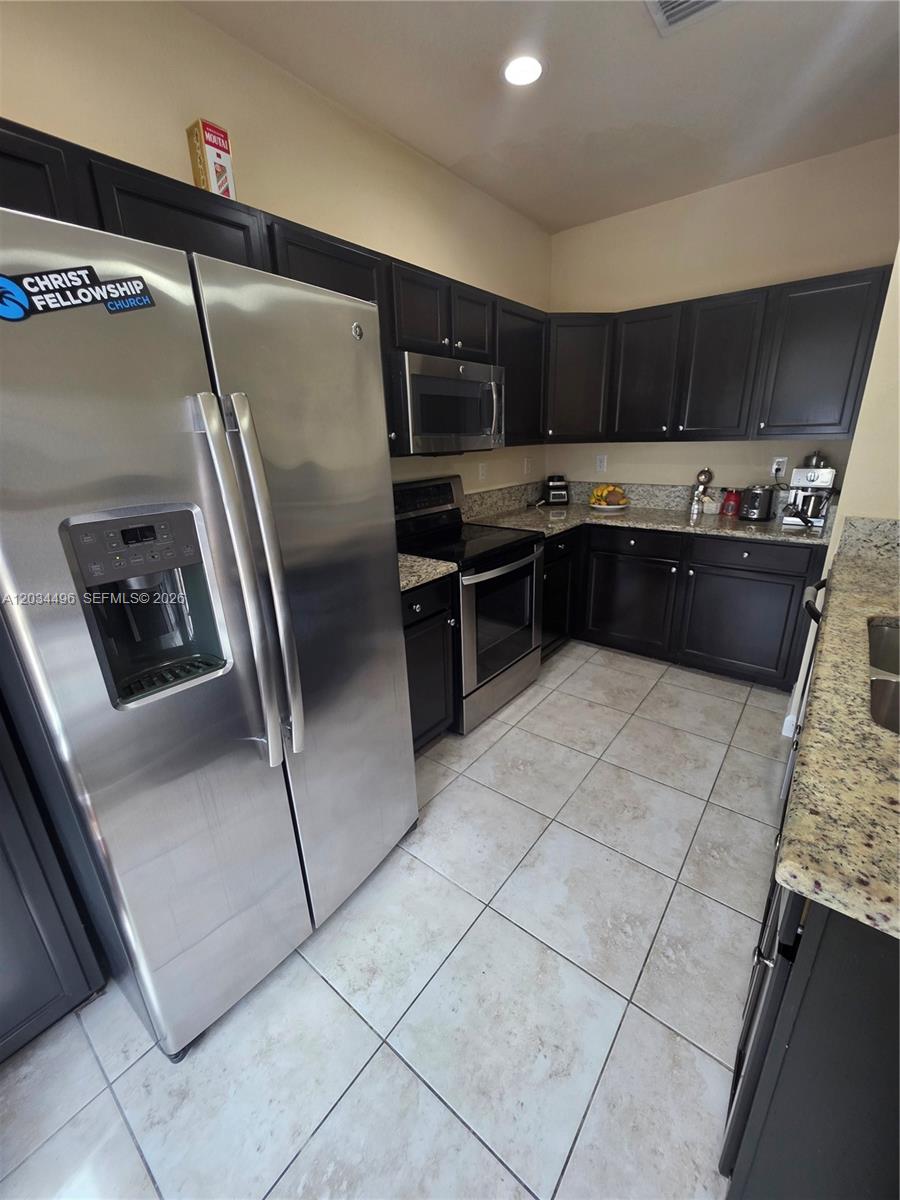 A kitchen features dark wood cabinets, stainless steel appliances, and speckled granite countertops — 9424 SW 171st Pl, Miami FL 33196, MIAMI, FL