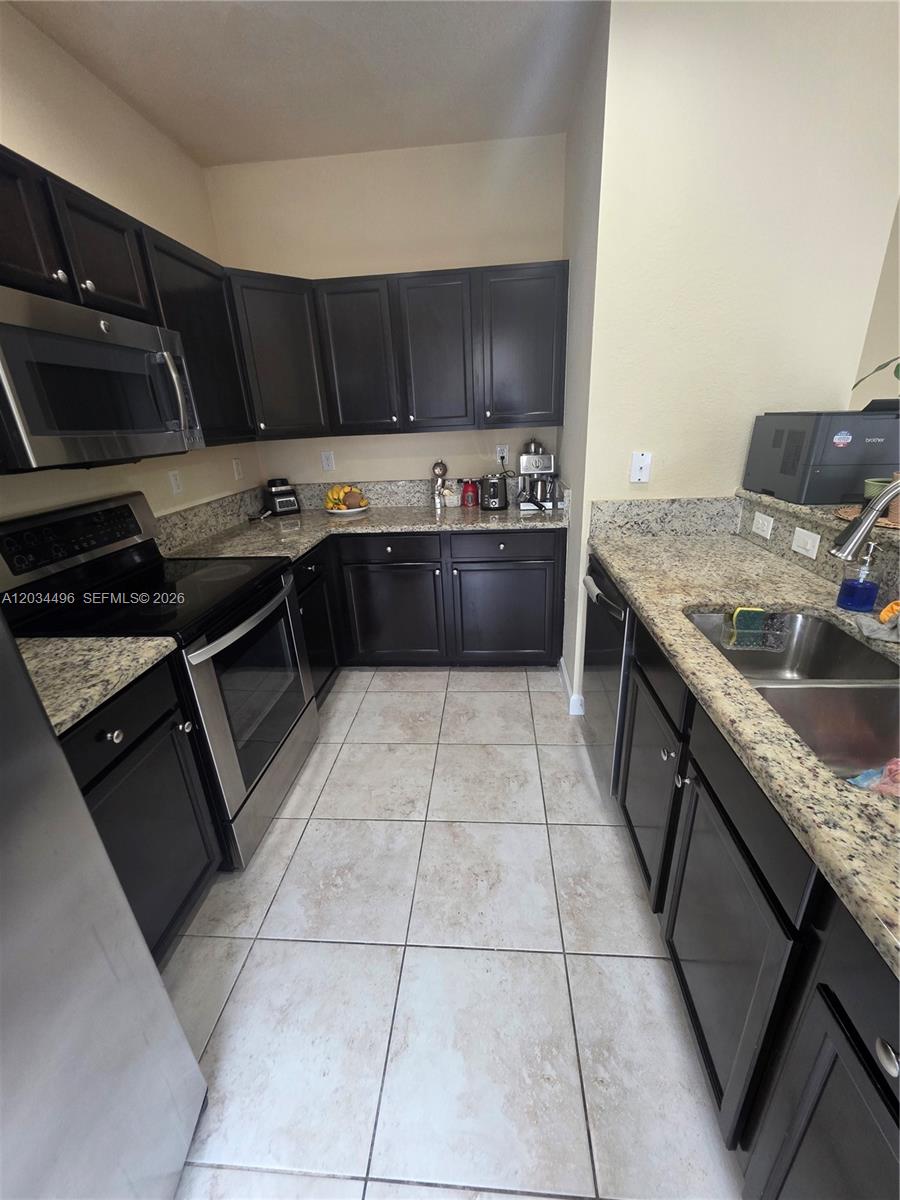 A kitchen features dark wood cabinets, granite countertops, stainless steel appliances, and tiled flooring — 9424 SW 171st Pl, Miami FL 33196, MIAMI, FL