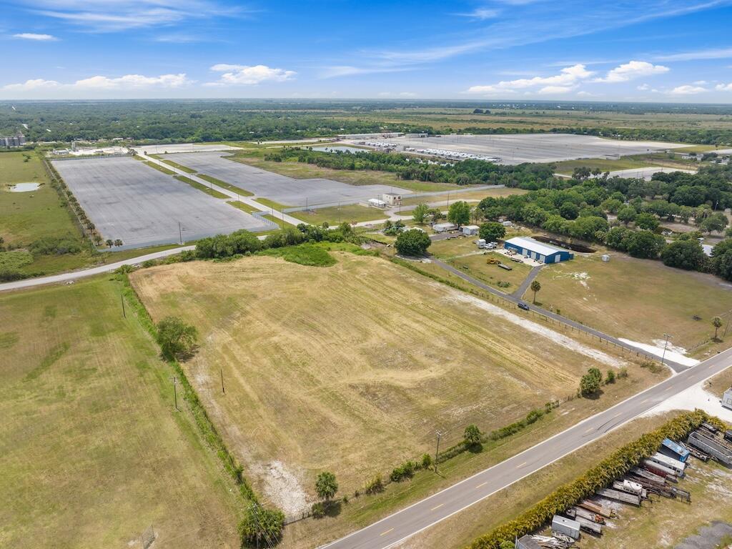 An aerial view shows a large, vacant grassy lot adjacent to a road and industrial buildings — 3274 NW 18th Street, Okeechobee FL 34972, OKEECHOBEE, FL