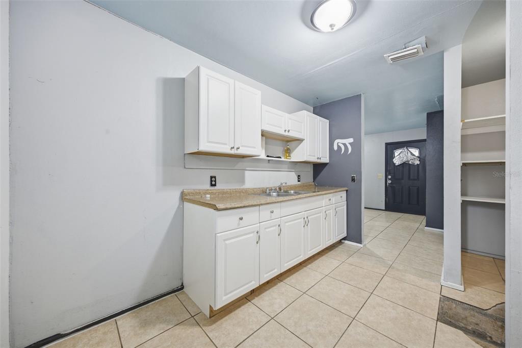 A kitchen features white cabinets, a tan countertop, and light-colored tile flooring — 307 W ALFRED STREET, TAMPA, FL