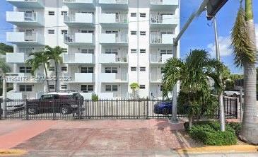 A multi-story white apartment building stands behind a black metal fence with palm trees — 801 Meridian Ave # 3B, Miami Beach FL 33139, MIAMI BEACH, FL
