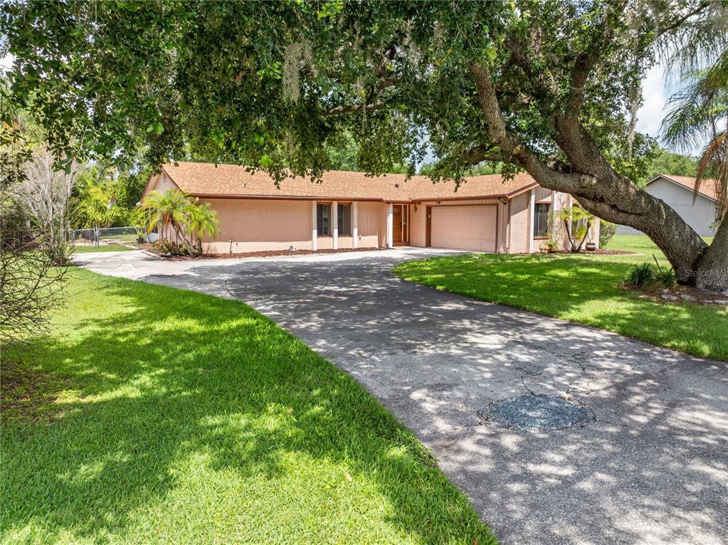 A single-story brick house with a brown shingle roof and a large paved driveway — 2440 CRANE COURT, ST CLOUD, FL