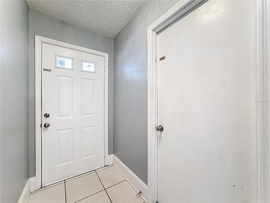 A white front door and an adjacent interior door in a small tiled entryway — 3717 NARROLINE DRIVE, ORLANDO, FL