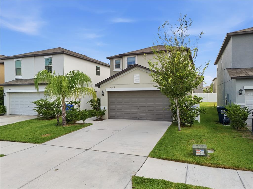 A two-story suburban house with a tan exterior, a two-car garage, and a front lawn — 7023 SAMUEL IVY DRIVE, TAMPA, FL