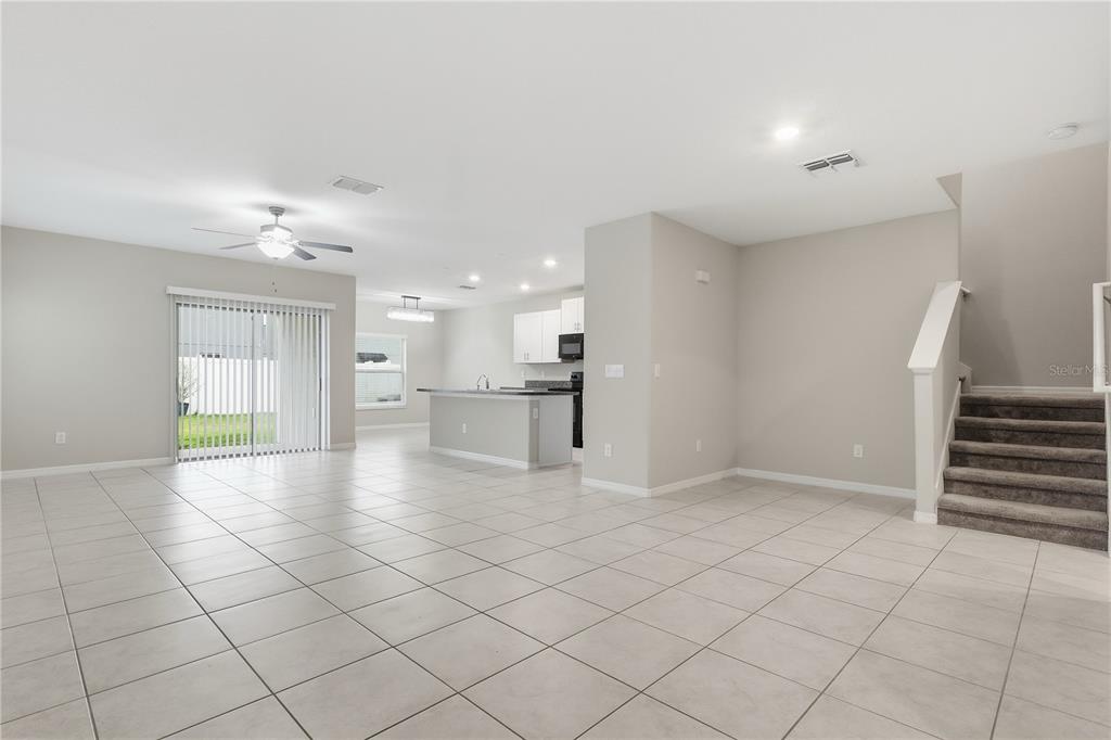 An open-concept living area features light tile flooring, a kitchen island, and a carpeted staircase — 7023 SAMUEL IVY DRIVE, TAMPA, FL