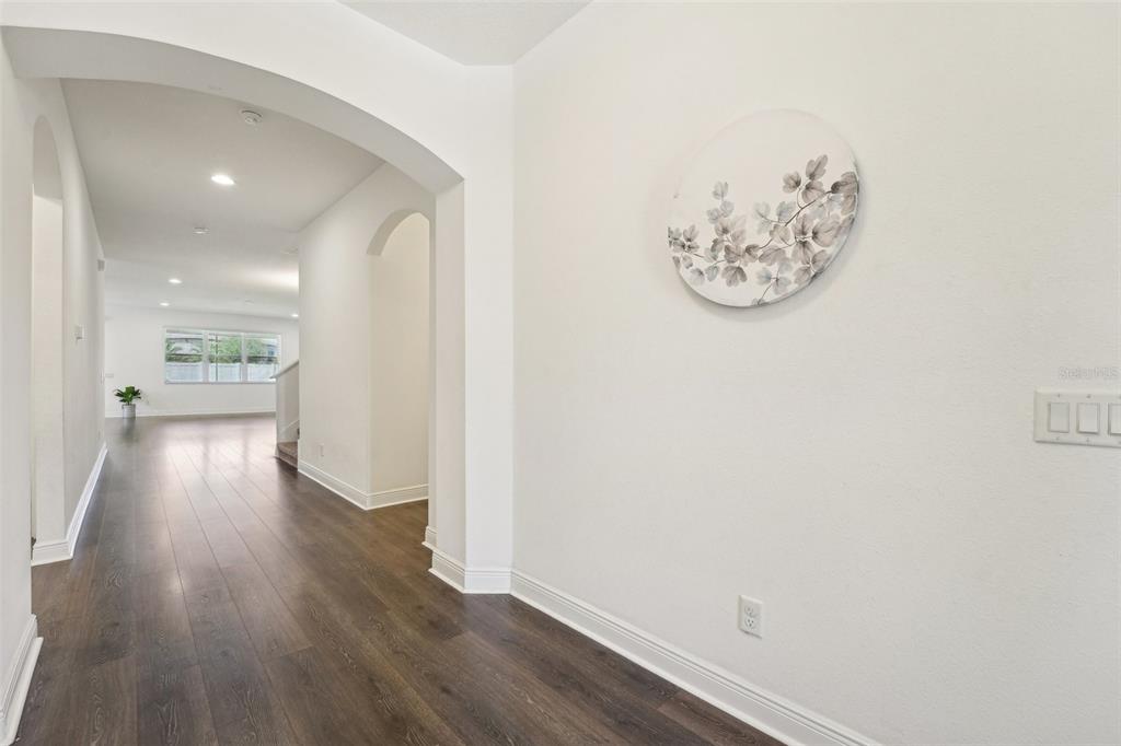 A hallway with dark wood-look flooring leads to an arched opening into a bright room — 1741 CHERRY WALK ROAD, LUTZ, FL