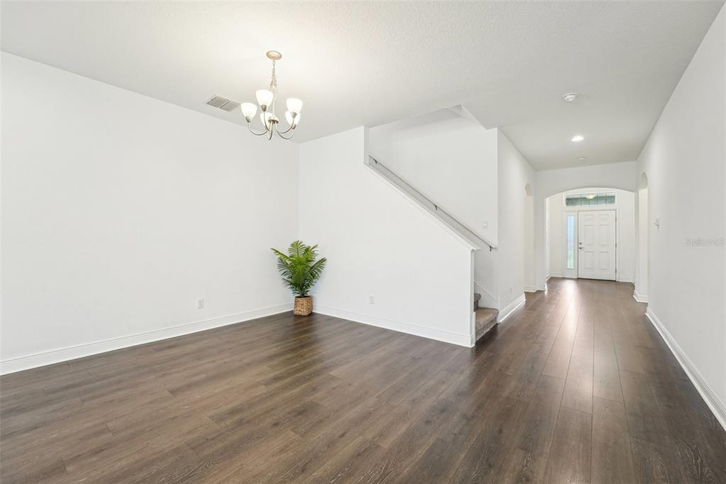 An empty room with dark wood-look flooring, white walls, a chandelier, and a staircase — 1741 CHERRY WALK ROAD, LUTZ, FL