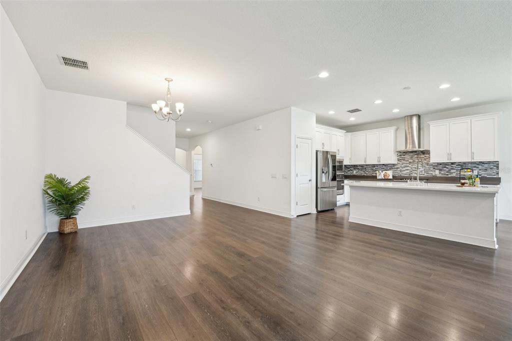 An open-concept kitchen and living area features white cabinetry, stainless appliances, and dark wood flooring — 1741 CHERRY WALK ROAD, LUTZ, FL