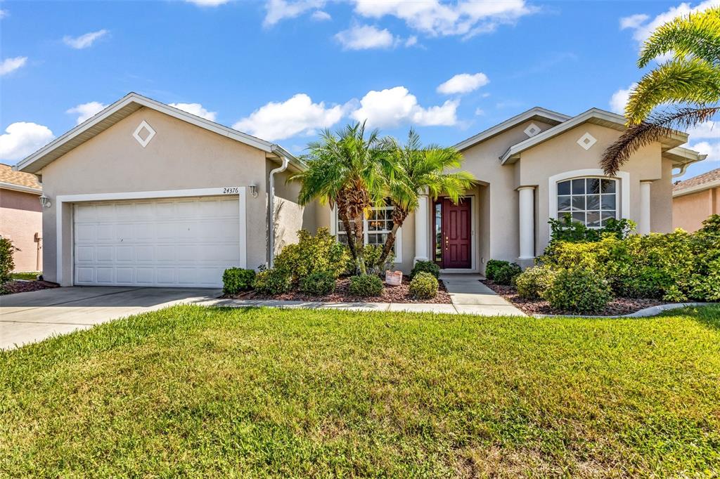 A single-story house with a white garage, a red front door, and palm trees — 24376 WESTGATE BOULEVARD, PUNTA GORDA, FL