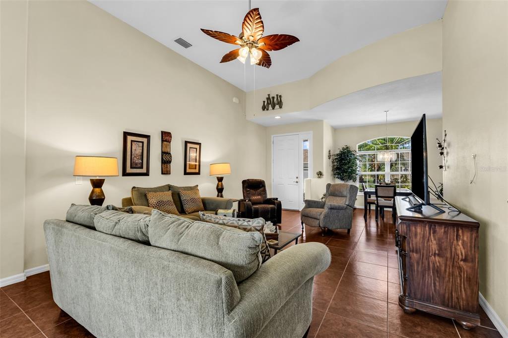 A living room with tile floors, a vaulted ceiling, a ceiling fan, and neutral walls — 24376 WESTGATE BOULEVARD, PUNTA GORDA, FL