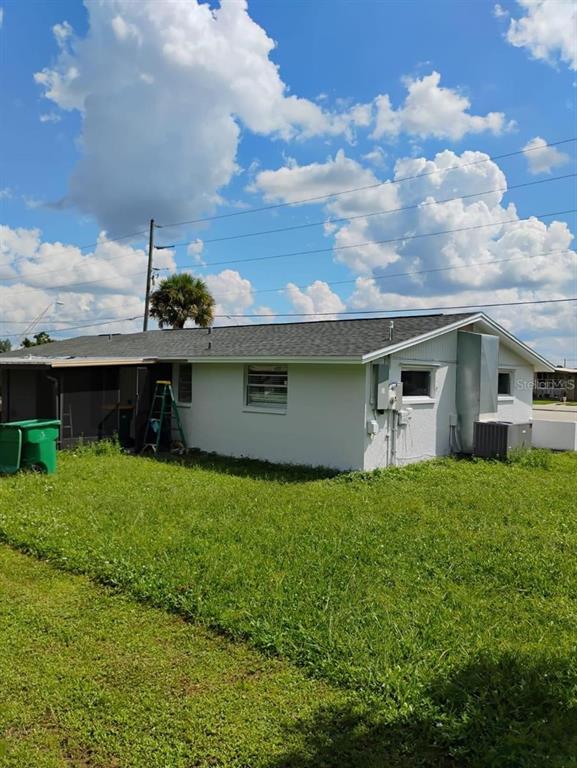 The exterior of a single-story house with a white facade and a gray shingled roof — 21440 MIDWAY BOULEVARD, PORT CHARLOTTE, FL